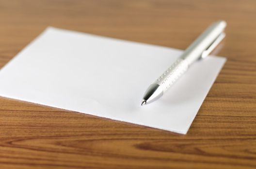 pen with white paper on wooden background