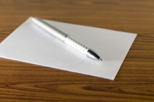 pen with white paper on wooden background