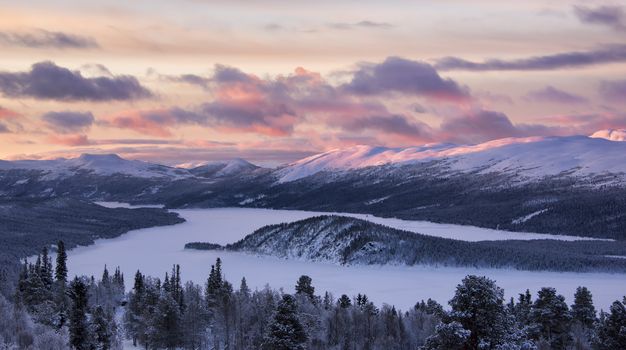 Early morning with the first sun over snow covered mountains landscape in Norway