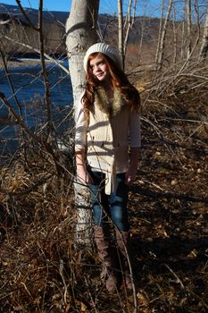 Winter girl leaning against a tree with river in the background 