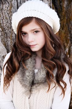 Winter girl leaning against a large tree 