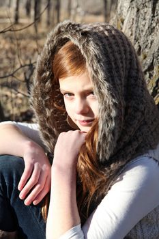 Beautiful teen girl sitting against a tree