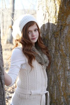 Winter girl leaning against a large tree 