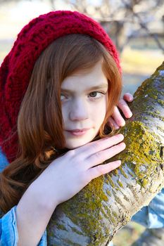 Teen girl leaning against a tree branch
