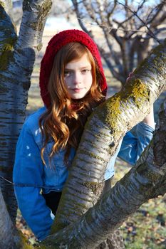 Teen girl leaning against a tree branch