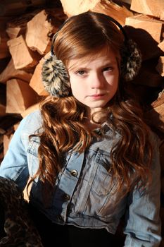 Red haired girl wearing earmuffs against wooden background 