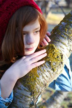 Teen girl leaning against a tree branch