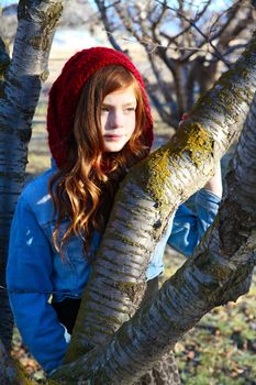 Teen girl leaning against a tree branch