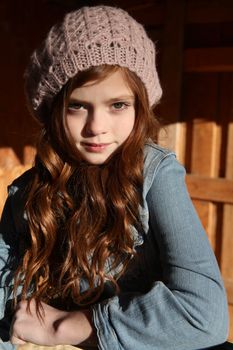 Winter girl leaning against a wooden fence 