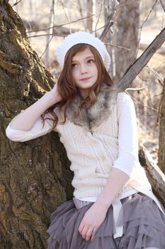 Winter girl leaning against a large tree 