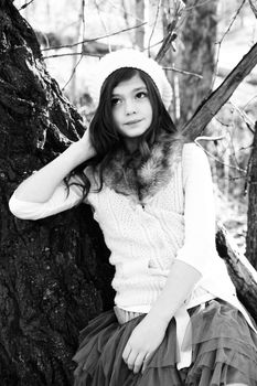 Winter girl leaning against a large tree 