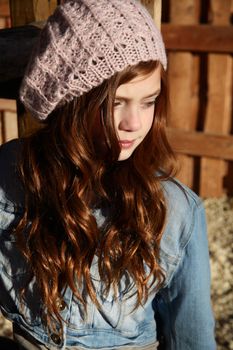 Winter girl leaning against a wooden fence 