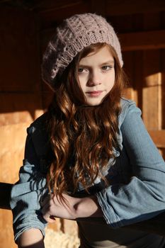 Winter girl leaning against a wooden fence 