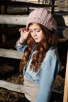 Winter girl leaning against a wooden fence 