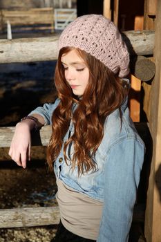 Winter girl leaning against a wooden fence 