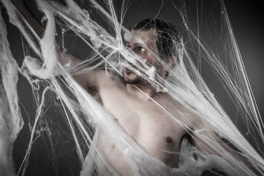 Scary network.man tangled in huge white spider web