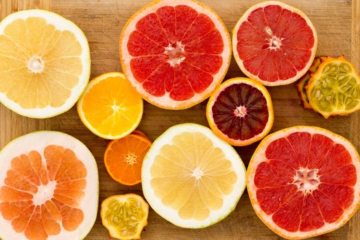 Colorful festive assortment of halved citrus fruit arranged on a wooden board with a variety of grapefruit, orange, pomelo and kiwano or horned melon viewed from above