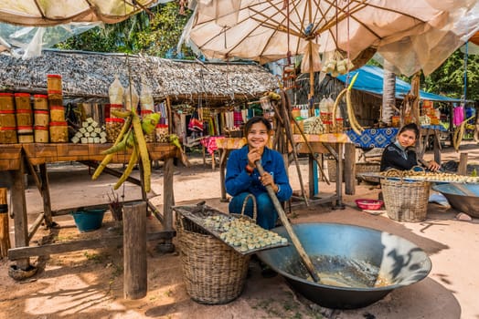 Angkor, Cambodia - January 2, 2014: girl making and selling sugar cane sweets at Angkor Cambodia on january 2nd, 2014