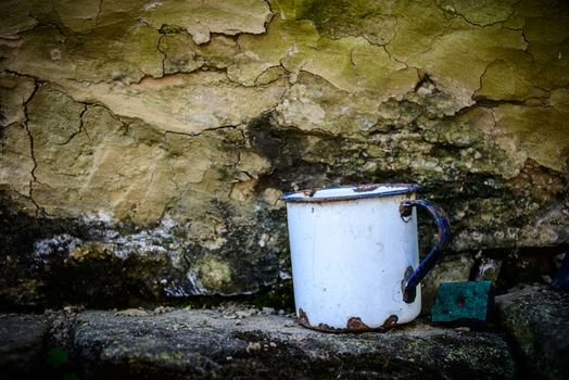 Old enamelware mug against a grungy wall