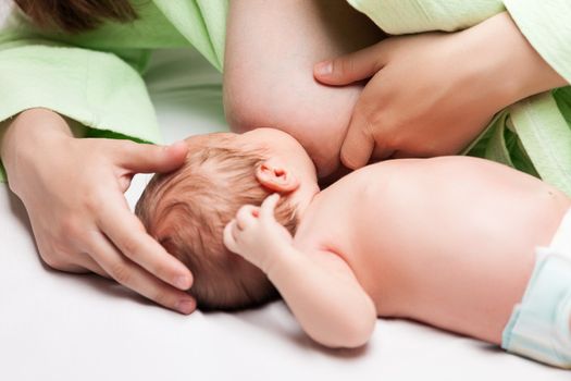 Baby breastfeeding - little newborn child sucking or eating mother breast milk