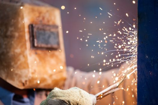 Heavy industry welder worker in protective mask hand holding arc welding torch working on metal construction