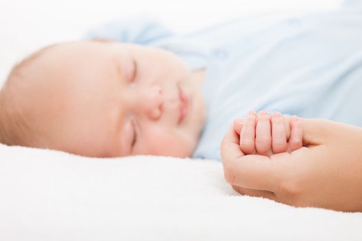 Loving mother hand holding cute sleeping newborn baby child