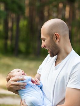 Family happiness - loving father bonding or holding little newborn baby child boy walking outdoor