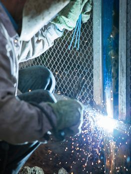 Heavy industry welder worker in protective mask hand holding arc welding torch working on metal construction