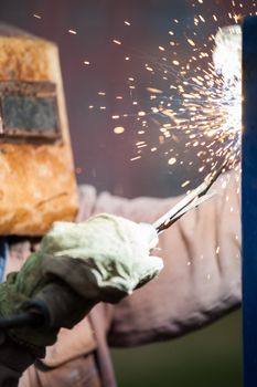 Heavy industry welder worker in protective mask hand holding arc welding torch working on metal construction