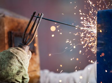 Heavy industry welder worker in protective mask hand holding arc welding torch working on metal construction