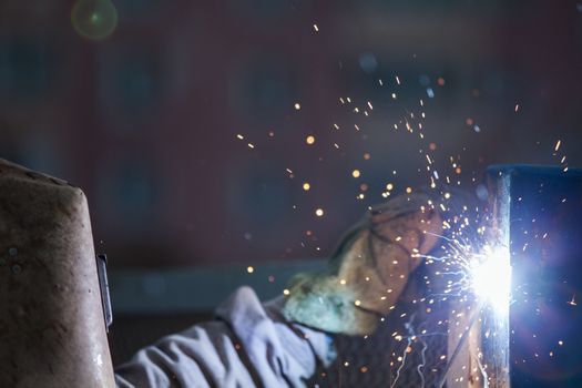 Heavy industry welder worker in protective mask hand holding arc welding torch working on metal construction