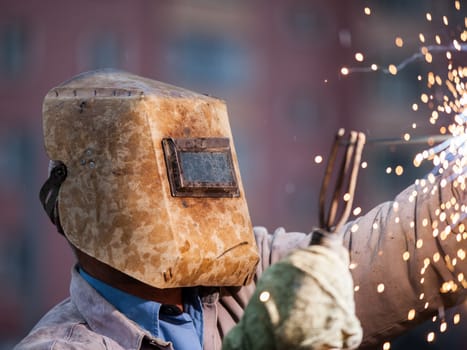 Heavy industry welder worker in protective mask hand holding arc welding torch working on metal construction