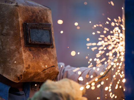 Heavy industry welder worker in protective mask hand holding arc welding torch working on metal construction