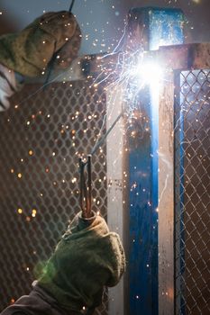 Heavy industry welder worker in protective mask hand holding arc welding torch working on metal construction