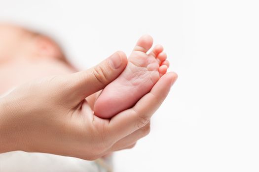 Loving mother hand holding cute sleeping newborn baby child little foot or heel