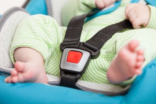 Little baby child fastened with security belt in safety car seat