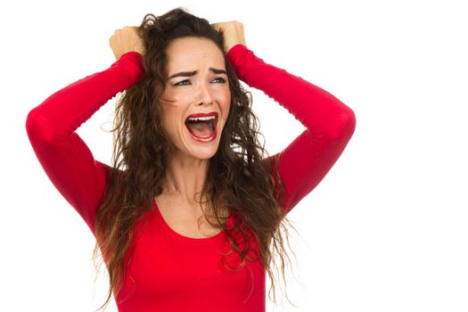 A very frustrated and angry and upset woman is screaming out loud and pulling her hair. Isolated on white.