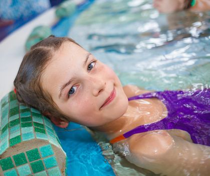 In aquapark. Smiling beautiful girl relaxing in pool.