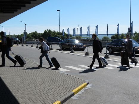 TALLINN, CIRCA JUNE 2012 - Travellers carrying their trolley at the zebra crossing in front of the airport in Tallinn, june 2012