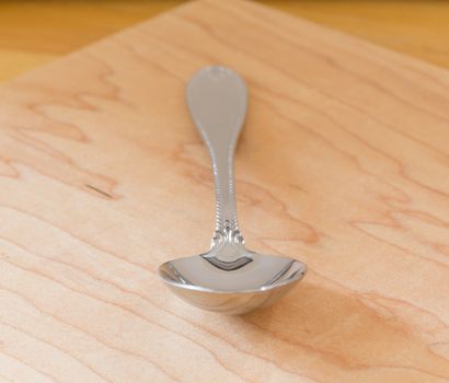 Decorated serving or dessert spoon in front view on wooden table or cutting board