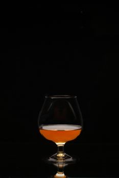 glass with brandy on the black background
