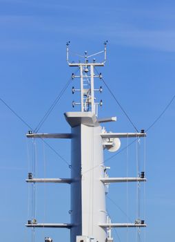 Communication tower or mast on large cruise ship with aerials and antennae against blue sky