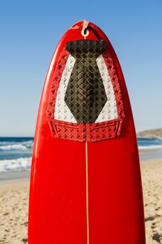 Red surfboard on the sand on a very beautiful sunny day