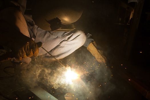 Welder with sparks arcing, industrial background