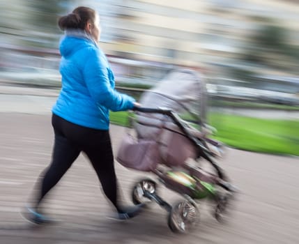 Mother with small children and a pram walking down the street. Intentional motion blur