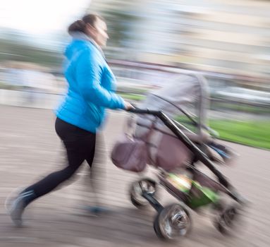 Mother with small children and a pram walking down the street. Intentional motion blur