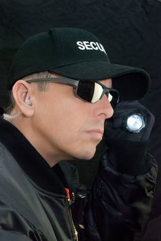 Close-up of a security guard searching with his flashlight.