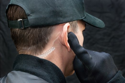Close-up of a security guard listening to his earpiece. Shot from, over the shoulder.