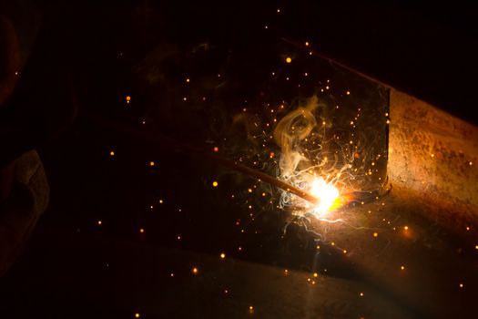 Welder with sparks arcing, industrial background