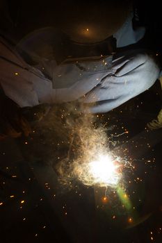 Welder with sparks arcing, industrial background